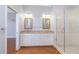 Bright bathroom featuring a double vanity, framed mirrors, and frameless glass shower at 1930 Massachusetts Ave, Englewood, FL 34224
