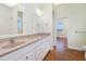 Well-lit bathroom with double sinks, framed mirror, and view into a large bedroom at 1930 Massachusetts Ave, Englewood, FL 34224
