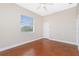 A cozy bedroom featuring a ceiling fan, window views, and dark sealed concrete floors with white trim at 1930 Massachusetts Ave, Englewood, FL 34224