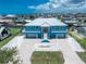 Bright blue waterfront home featuring a metal roof, double garage, and a spacious, paved driveway at 1930 Massachusetts Ave, Englewood, FL 34224