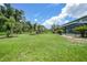 Large backyard featuring lush greenery, palm trees, and manicured garden beds at 196 Lecturn St, Port Charlotte, FL 33954