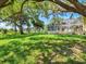 Expansive backyard with lush lawn and mature trees bordering the screened pool area at 23 Pine Valley Ct, Rotonda West, FL 33947