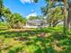Spacious backyard featuring lush lawn and mature trees that surround the screened-in lanai and pool at 23 Pine Valley Ct, Rotonda West, FL 33947
