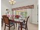 Dining area displaying an ornate dark wood table set for a meal overlooking the pool and outdoor patio at 23 Pine Valley Ct, Rotonda West, FL 33947