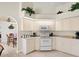 Bright kitchen with all-white appliances, custom cabinets, and a view into the formal dining area at 23 Pine Valley Ct, Rotonda West, FL 33947
