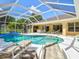 Relaxing outdoor pool area with covered lanai, lounge chairs, and a tranquil setting at 23 Pine Valley Ct, Rotonda West, FL 33947