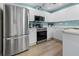 Well-lit kitchen with stainless steel appliances, white cabinetry, and light wood flooring at 237 Park Forest Blvd, Englewood, FL 34223