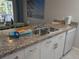 Well-lit kitchen with stainless steel sink, white cabinets, and lovely countertops at 2373 N Beach Rd # 1C, Englewood, FL 34223