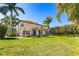 Expansive backyard view showcasing lush lawn, mature trees, and a screened lanai ideal for relaxation at 26294 Bridgewater Rd, Punta Gorda, FL 33983
