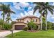 Beautiful two-story home featuring a manicured lawn, two car garage and lush tropical landscaping at 26294 Bridgewater Rd, Punta Gorda, FL 33983