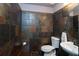 Unique half bathroom with stone tiled walls, modern toilet, and bright vanity lighting at 26294 Bridgewater Rd, Punta Gorda, FL 33983
