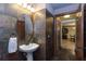 Stylish half bath with stone tile walls, vessel sink, and dark wood trim and door at 26294 Bridgewater Rd, Punta Gorda, FL 33983