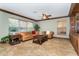 Cozy living room with tile flooring, a ceiling fan, and comfortable leather furniture by large windows at 26294 Bridgewater Rd, Punta Gorda, FL 33983