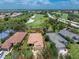 Expansive aerial view of property showcasing lush landscaping, golf course, and serene lake views at 3207 Village Ln, Port Charlotte, FL 33953