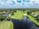 Aerial view of a scenic golf course with lush greenery, a lake, and community homes at 3207 Village Ln, Port Charlotte, FL 33953