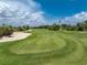 Scenic view of a well-maintained golf course featuring green grass, a sand trap, and a flag at 3207 Village Ln, Port Charlotte, FL 33953