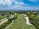 Overhead view of a golf course winding alongside a road on a sunny day with fluffy clouds at 3207 Village Ln, Port Charlotte, FL 33953