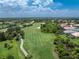 Panoramic aerial view of a golf course nestled among houses and trees, showcasing the green landscape at 3207 Village Ln, Port Charlotte, FL 33953