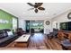 Inviting living room with a ceiling fan, wood floors and golf course views through the sliding glass doors at 3207 Village Ln, Port Charlotte, FL 33953