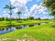 Scenic backyard with a tranquil canal view, lush green lawn, and mature trees creating a serene setting at 34 Broadmoor Ln, Rotonda West, FL 33947