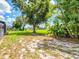 The spacious backyard features mature trees, lush vegetation, and a home in the distance at 34 Broadmoor Ln, Rotonda West, FL 33947