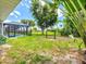 Fenced backyard with a screened-in pool area, green grass, and mature trees nearby at 34 Broadmoor Ln, Rotonda West, FL 33947