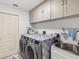 Well-organized laundry room with modern washer and dryer units, upper cabinets, and a utility sink at 34 Broadmoor Ln, Rotonda West, FL 33947