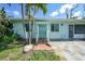 Inviting home featuring a decorative front door, covered entrance, and lush tropical landscaping at 55 Mark Twain Ln, Rotonda West, FL 33947