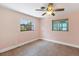 Simple bedroom with tile flooring, ceiling fan, and natural light from two windows at 70 Wilhelm Dr, Englewood, FL 34223
