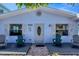 Quaint exterior featuring an oval front door, palm tree shutters, and green Adirondack chairs on a brick pathway at 70 Wilhelm Dr, Englewood, FL 34223