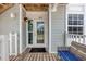 Charming front door with transom window, side lights, dark mat, and light sconce on a raised wood porch at 7554 Palm Island S Dr # 1813, Placida, FL 33946