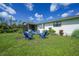 Lush backyard featuring a patio area with blue chairs and an open lawn at 7690 Castleberry Ter, Englewood, FL 34224