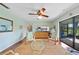 Bright living room featuring wood floors, ceiling fan, sitting area and access to the outdoor space through sliding glass doors at 7690 Castleberry Ter, Englewood, FL 34224