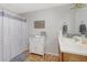 Bright bathroom with a white vanity, decorative shower curtain, and linen cabinet at 8224 Pinetree Ln, Englewood, FL 34224