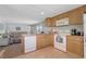 Practical kitchen with wood cabinetry, white appliances, and an open view to the living area at 8224 Pinetree Ln, Englewood, FL 34224