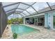Outdoor pool with a screened-in lanai, fireplace, and television at 10079 Lebanon Dr, Port Charlotte, FL 33981