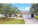 Charming single-story home with a well-maintained lawn, mature trees, and an attached two-car garage at 104 Mark Twain Ln, Rotonda West, FL 33947
