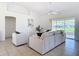 Open living room with tile flooring, neutral-tone furniture, and sliding doors to a screened lanai overlooking a lake at 104 Mark Twain Ln, Rotonda West, FL 33947