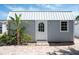 Close-up of charming backyard shed with a metal roof, brick pavers, and lush tropical landscaping at 1060 Haste Ln, Englewood, FL 34223