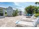 Charming backyard shed with a metal roof, brick pavers, and lush tropical landscaping at 1060 Haste Ln, Englewood, FL 34223