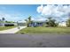 A cozy one-story home with a blue door, well-manicured lawn, and mature landscaping, set on a sunny street at 1060 Haste Ln, Englewood, FL 34223
