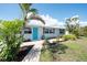 Charming one-story home with a bright blue front door, complemented by lush landscaping and a brick pathway at 1060 Haste Ln, Englewood, FL 34223