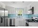 Kitchen with white cabinets, stainless steel appliances, and a blue tiled backsplash that adds a pop of color at 1060 Haste Ln, Englewood, FL 34223