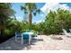 Charming patio with blue cushioned seating area, brick pavers, firepit, and lush tropical landscaping at 1060 Haste Ln, Englewood, FL 34223