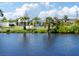 A tranquil canal view showcases a charming home with a blue door, framed by lush greenery and mature palms at 1060 Haste Ln, Englewood, FL 34223