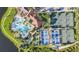 Aerial view of the community pool and tennis courts with palm trees, umbrellas, and lounge chairs at 10788 Tarflower Dr # 201, Venice, FL 34293