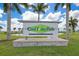 CoolToday Park community sign with manicured lawns, lush palm trees, and a scenic pond view at 12470 Wellen Golf St # 107, Venice, FL 34293