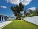 Large backyard featuring a well-maintained lawn, white fence, and large trees at 1295 S Maryknoll Rd, Englewood, FL 34223
