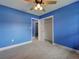 Bright bedroom with blue walls, ceiling fan, gray tile flooring, and a closet and open door at 1295 S Maryknoll Rd, Englewood, FL 34223