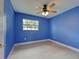 Bright bedroom with blue walls, ceiling fan, gray tile flooring, and a window at 1295 S Maryknoll Rd, Englewood, FL 34223